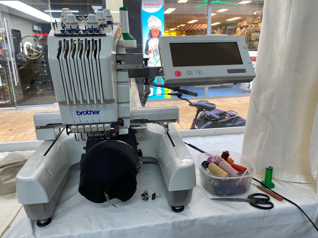 Een machine van Brother met een zwarte pet in de etalage van de winkel