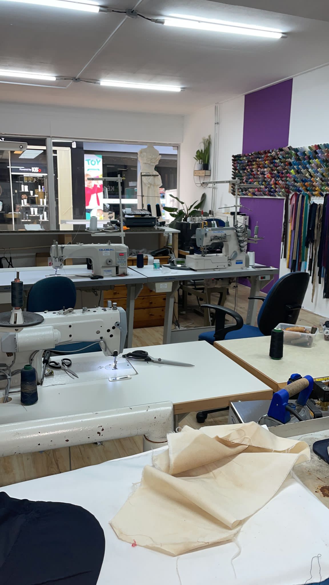 De werkplaats met naaitafels, industriële naaimachines en stof op de werktafel